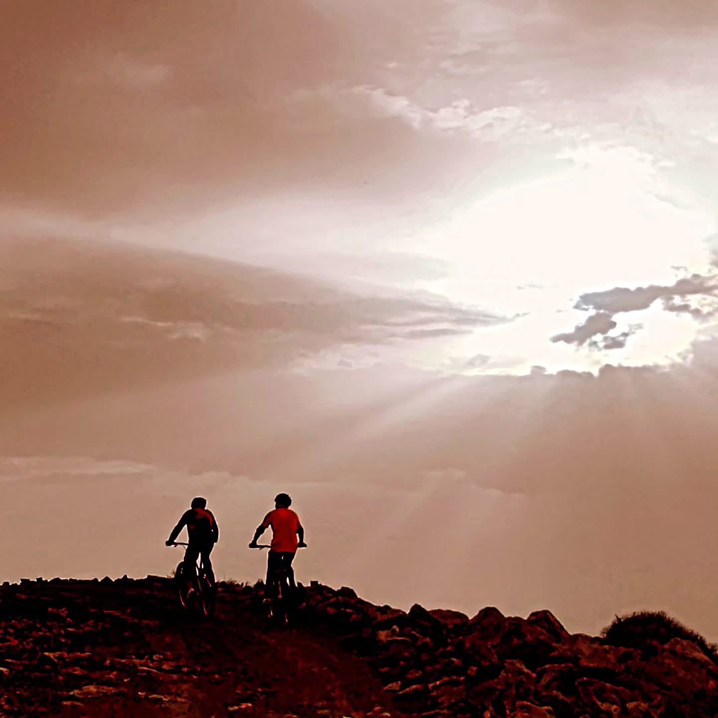 Deux cyclistes sur une crête rocheuse au coucher du soleil dans l'Atlas, Maroc